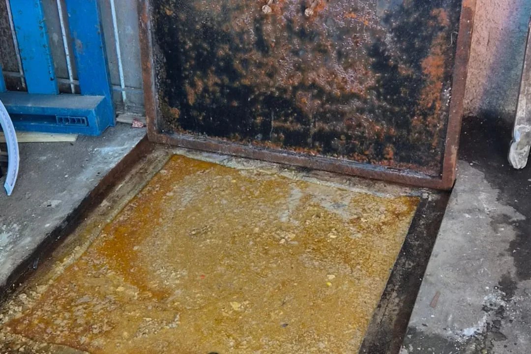 Caixa de gordura aberta e cheia, com uma camada grossa de gordura amarelada cobrindo toda a superfície