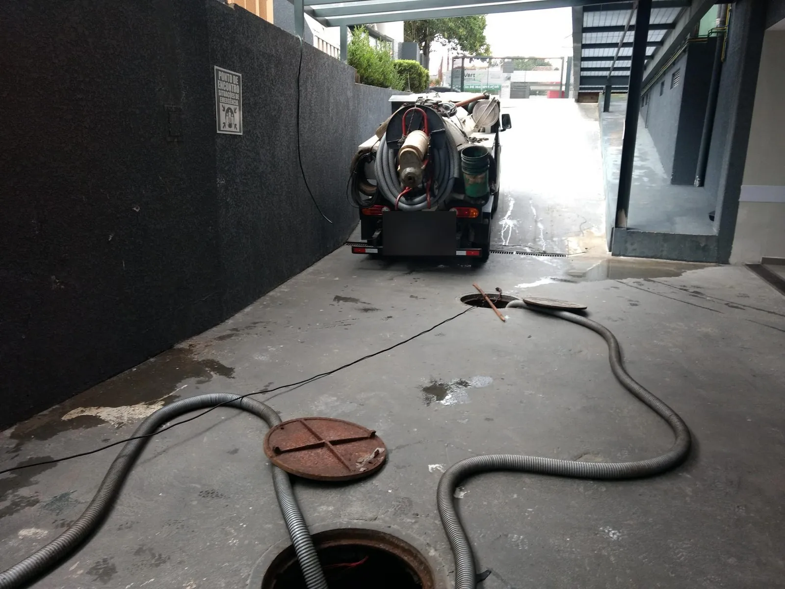 Mangueira descendo por um poço de visita de esgoto